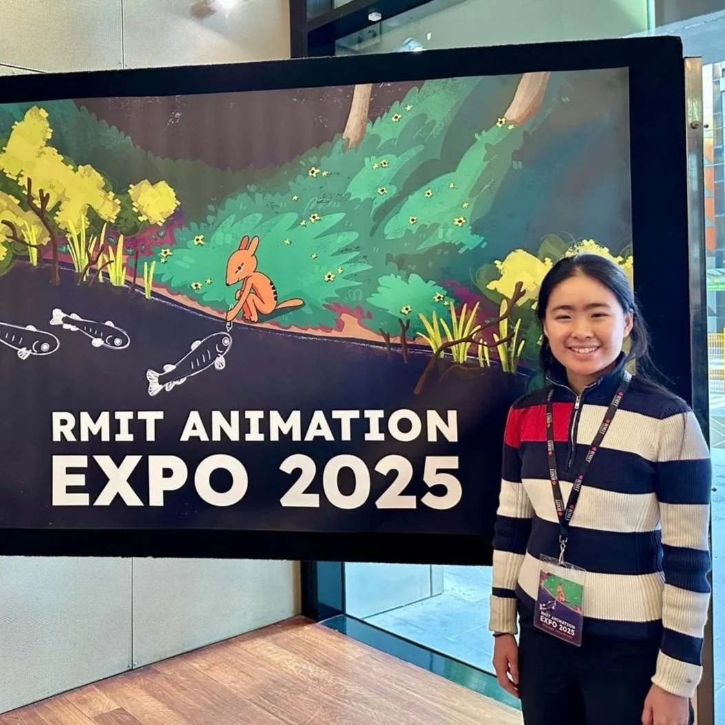 A young girl smiling standing in front of a colorful outdoor-themed poster for RMIT Animation Expo 2025. The poster features illustrations of a rabbit fishing in a pond with fish, trees, and plants.