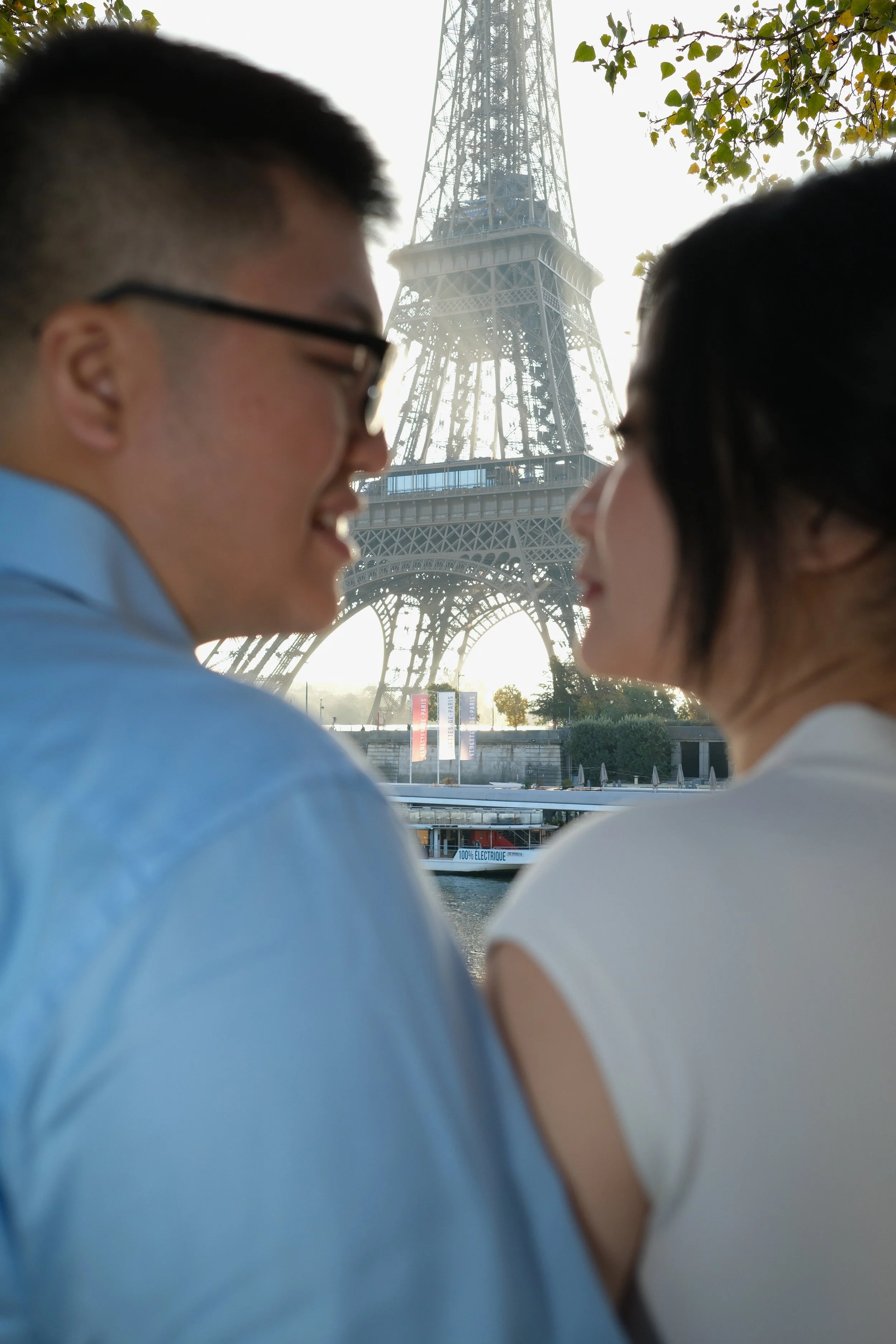 A man and woman facing each other with the Eiffel Tower in the background.