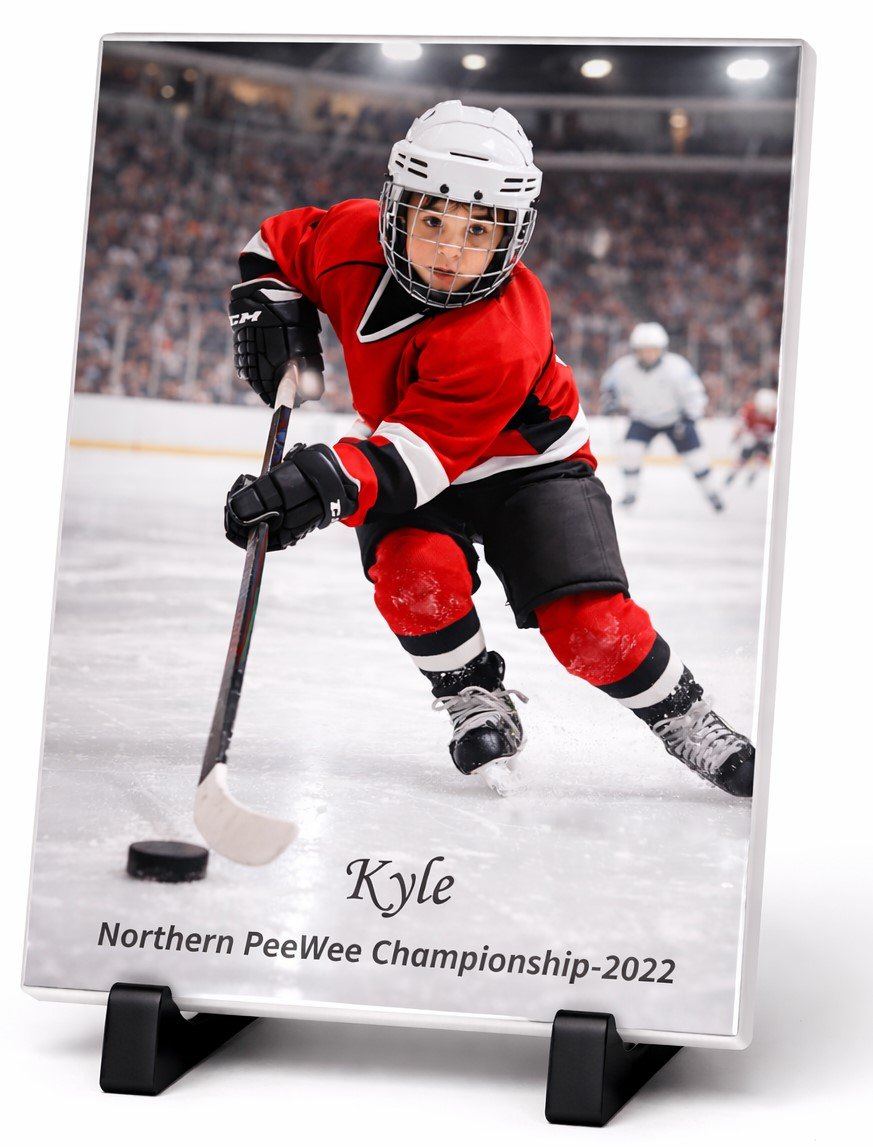 Photograph of a young boy in red hockey gear skating on ice with a hockey stick, in a hockey arena with spectators. Text on the photograph reads: "Kyle, Northern PeeWee Championship 2022."