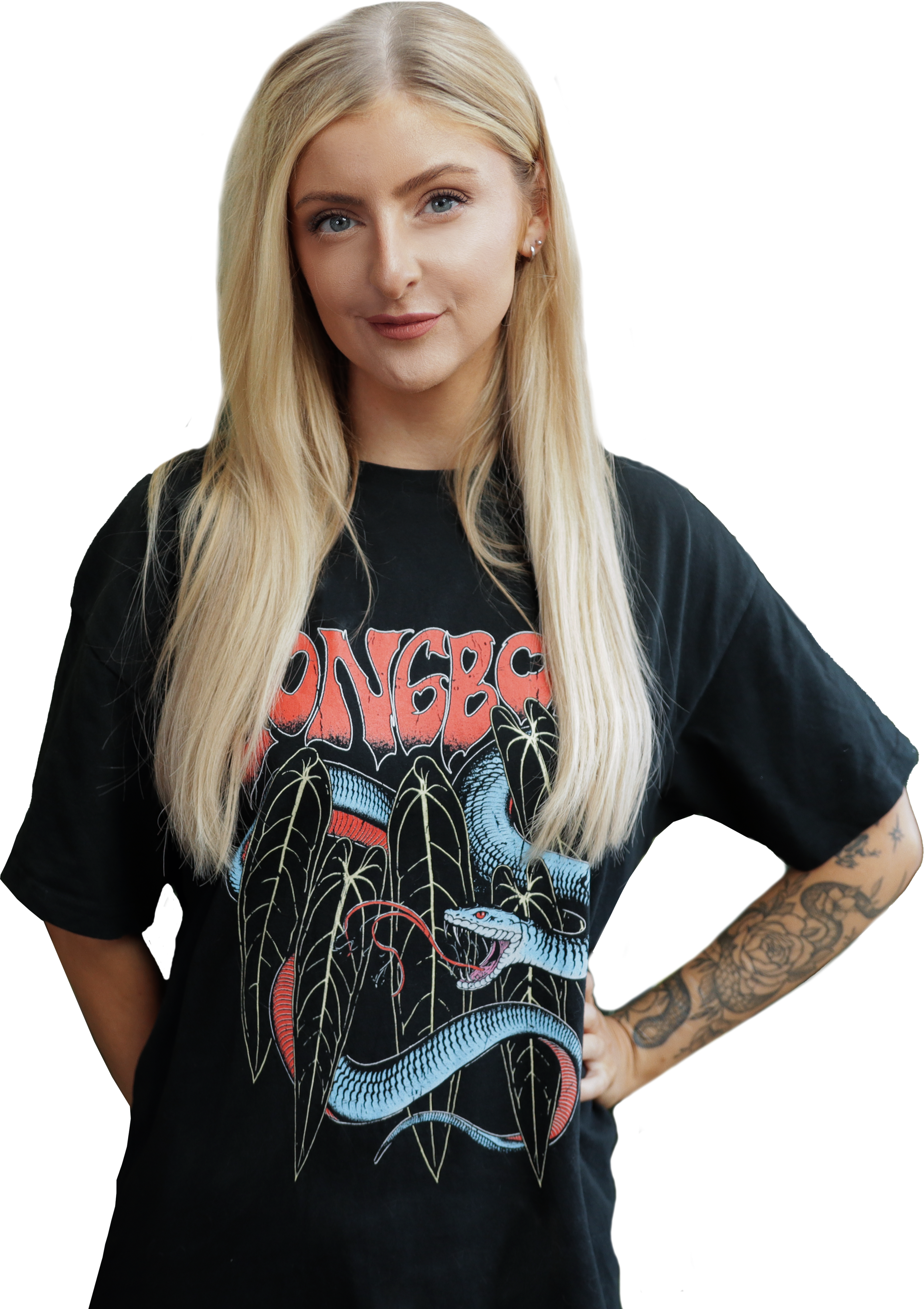 A young woman with long blonde hair, wearing a black band T-shirt with a colorful dragon and snake graphic, and showing a tattooed arm.