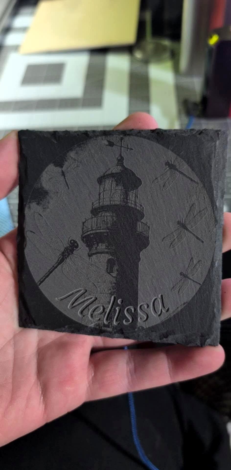Black slate engraved with a lighthouse scene and the name Melissa