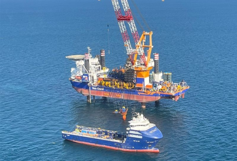 Offshore oil rig with a crane and equipment, accompanied by a large boat nearby in the ocean.