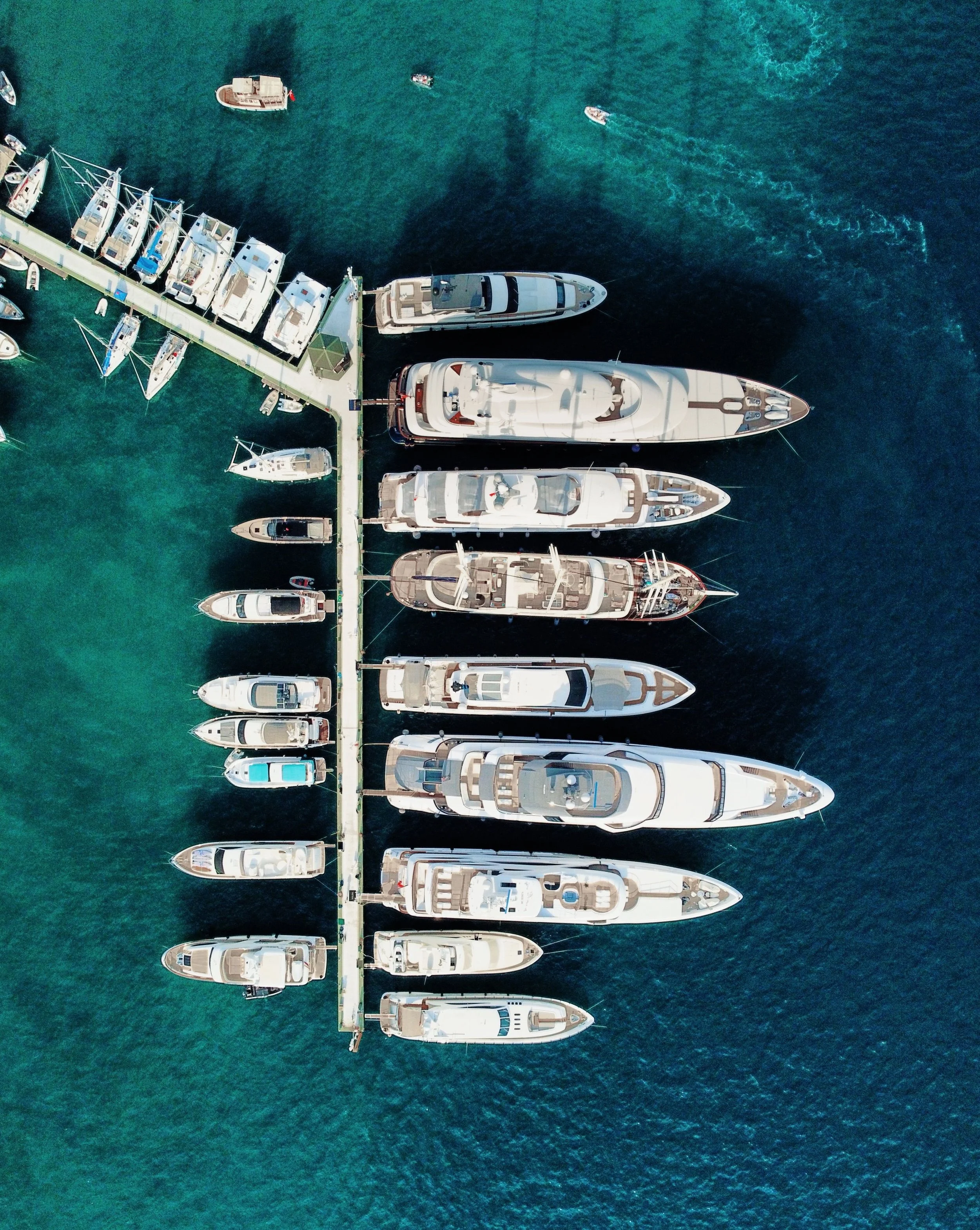 Aerial view of superyachts berthed along a marina pontoon