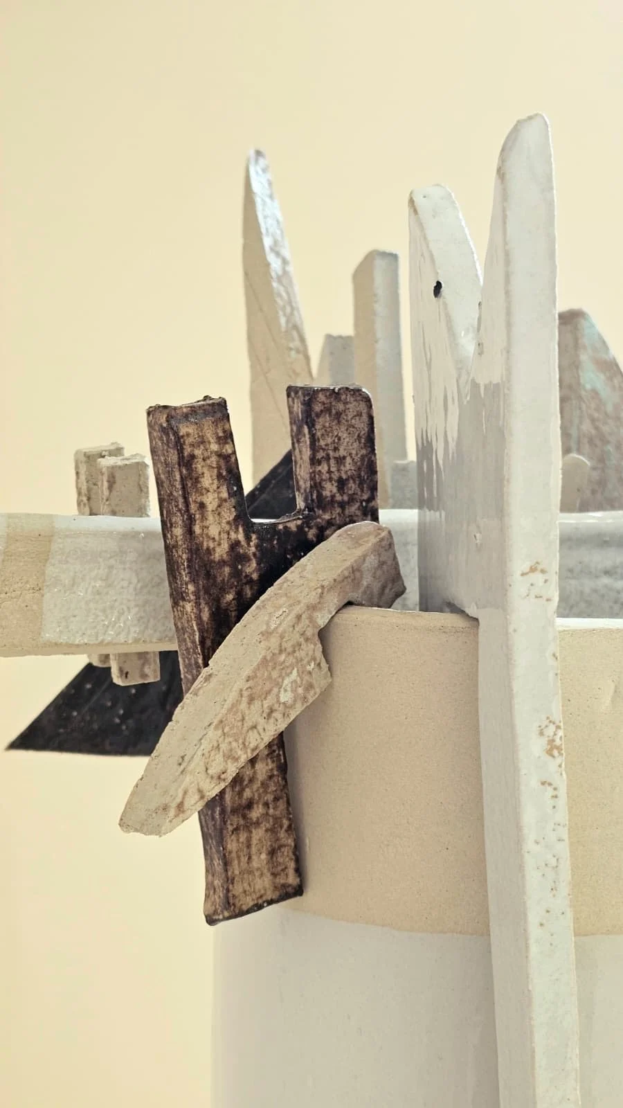 Close-up view of intersecting wooden and ceramic pieces with a white background.