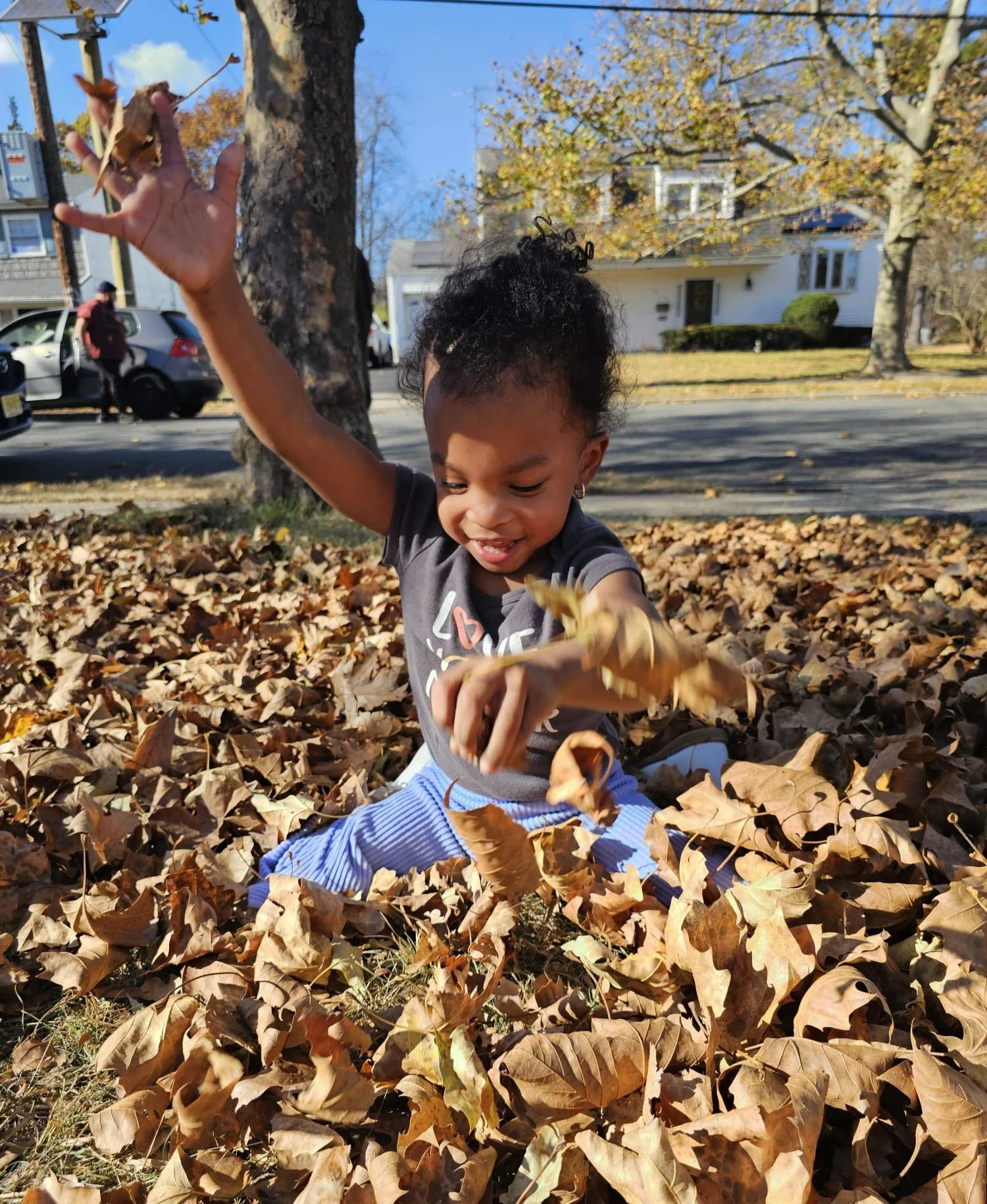 baby w sitting and playing with autumn leaves