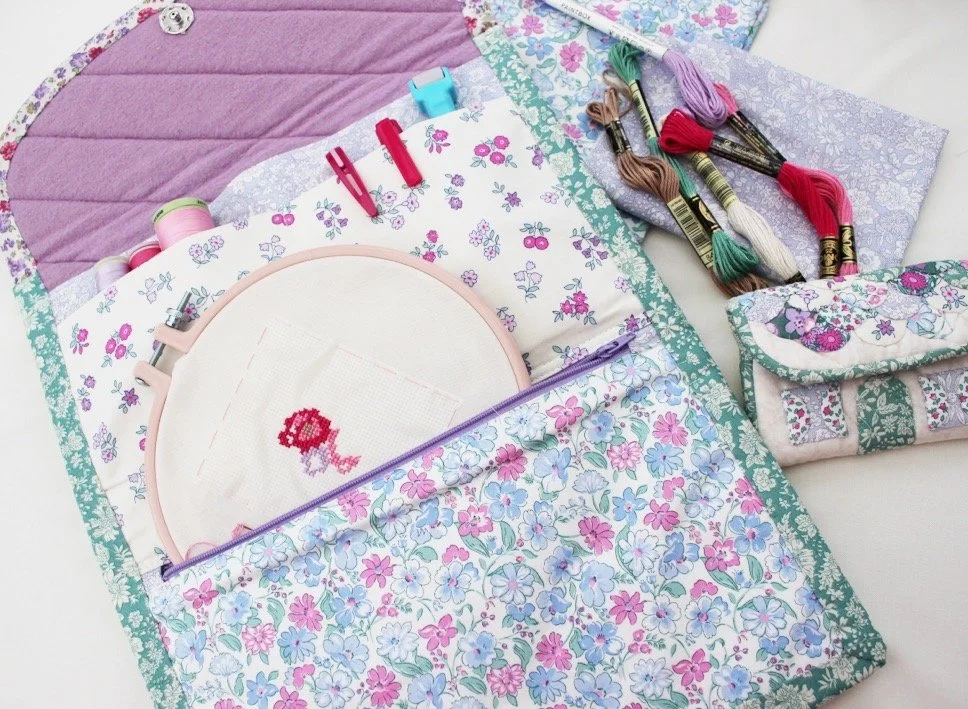 Embroidery kit with floral fabric, embroidery hoop, cross-stitch pattern, embroidery floss, and sewing accessories.