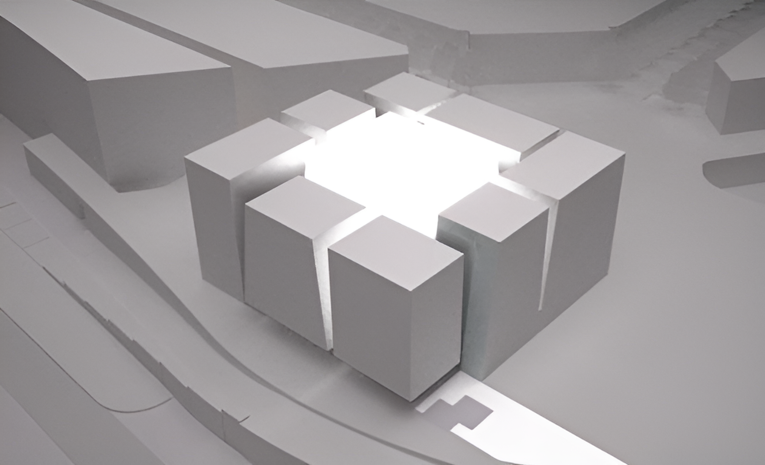 A white architectural model of a building complex with a central courtyard, surrounded by rectangular buildings on all sides.