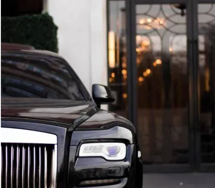 Una lussuosa auto nera parcheggiata davanti a un edificio con grandi vetrate