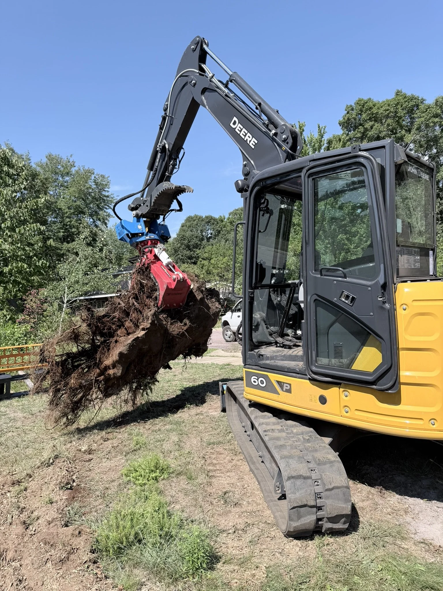 John Deere 60P with a CMP Attachments Hydra Grapple holding a stump it just dug out 