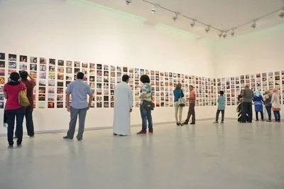 People viewing artwork displayed on gallery walls in an art exhibit.