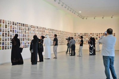 People viewing photos on a gallery wall in an art exhibition