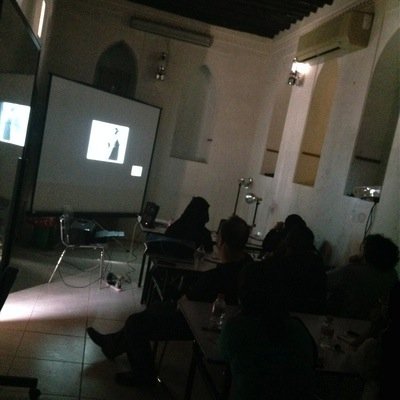 People are sitting in a dark room watching a presentation projected on a screen.