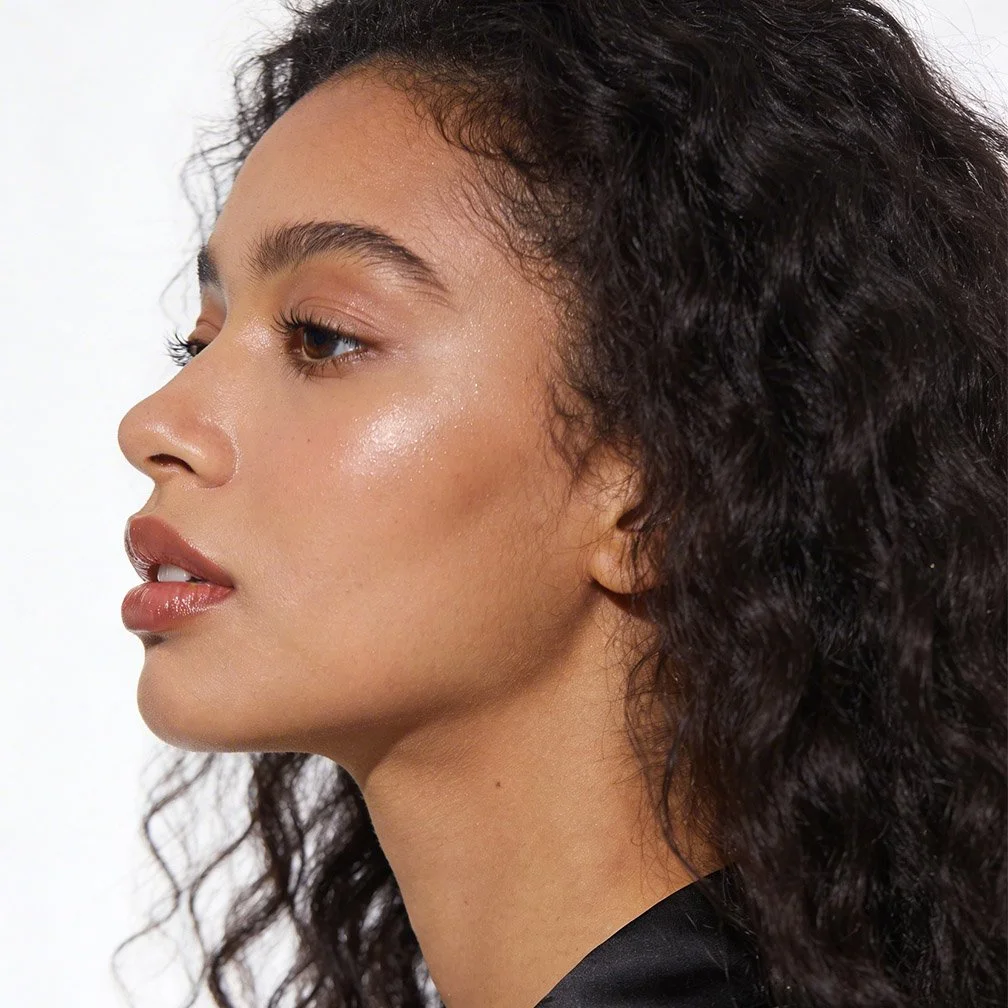 Close-up side profile of a woman with curly dark hair and light brown skin.