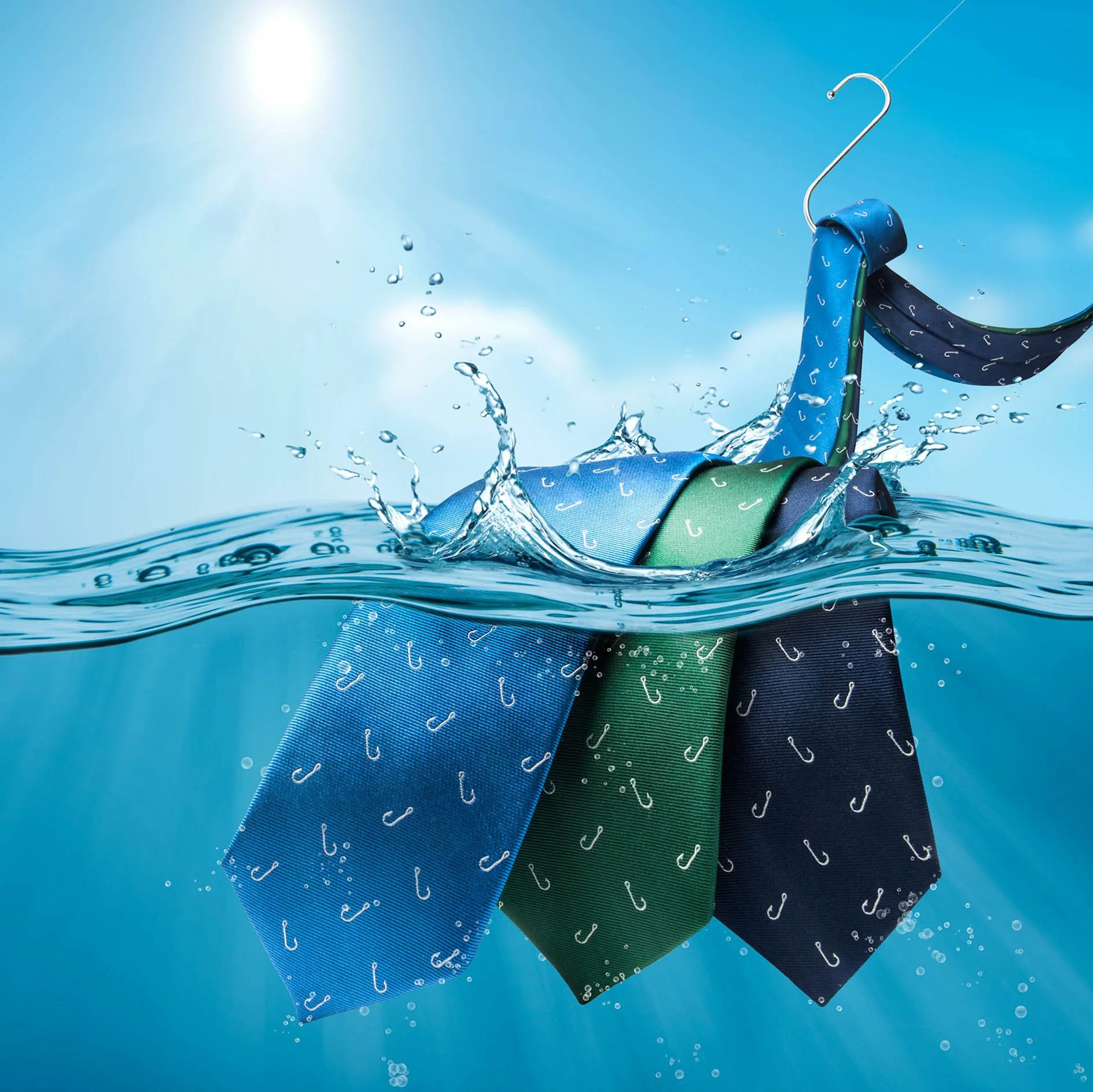Colorful neckties hanging on a hanger submerged in water with splash effects, under bright sunlight.