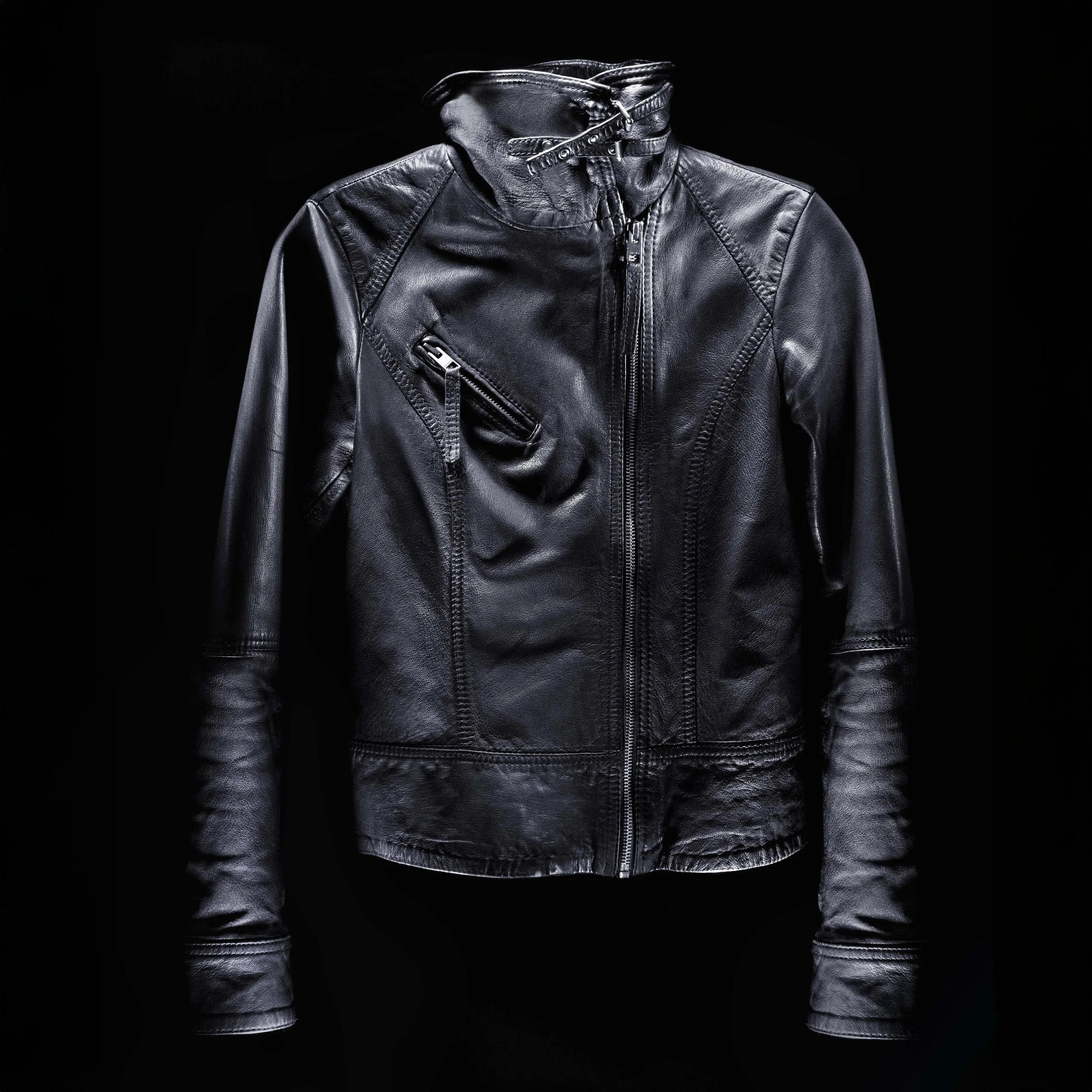 Black leather jacket with zippered pockets and high collar against black background.