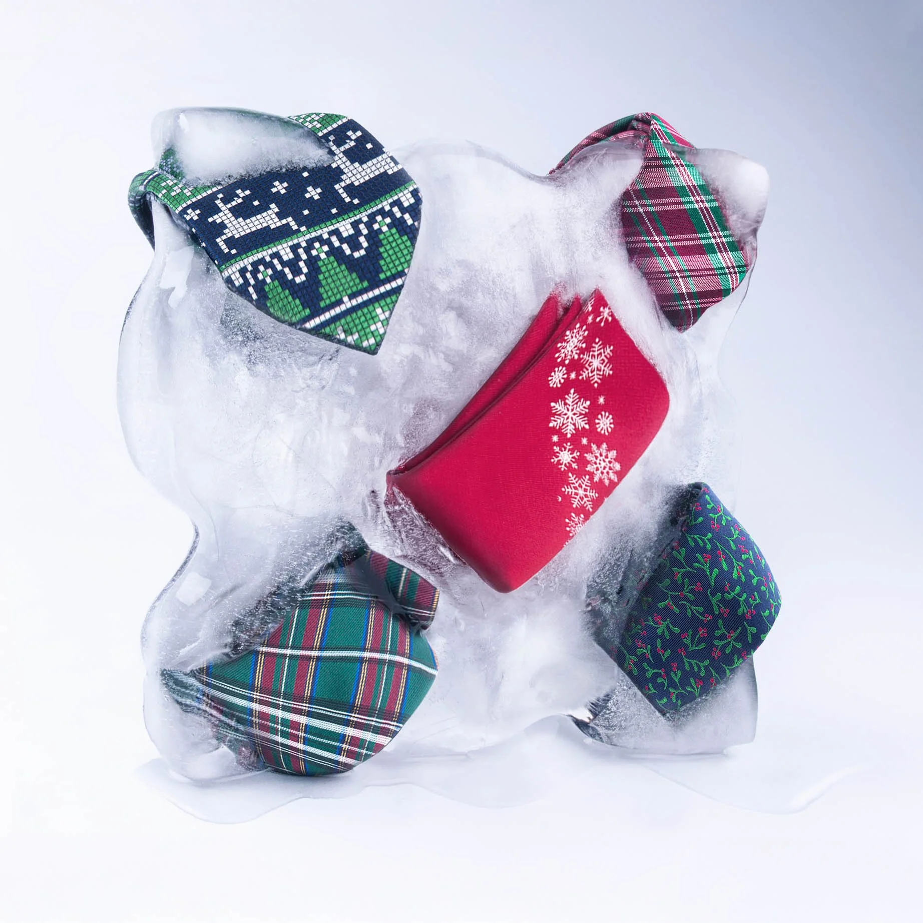 Ice sculpture with five holiday-themed fabric pouches in Christmas patterns, including snowflakes, plaid, and holly, set against a white background.