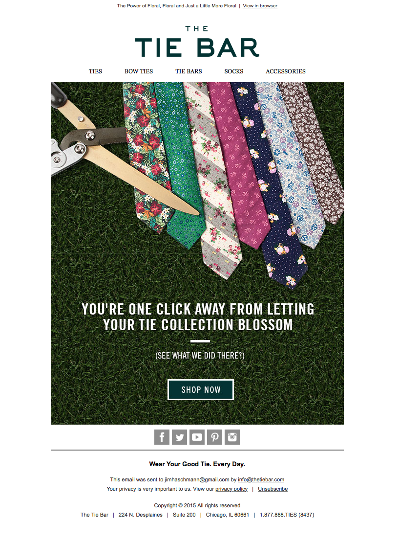 A website homepage for The Tie Bar featuring colorful fabric ties laid out on grass, with a pair of scissors cutting a beige tie on the left side.