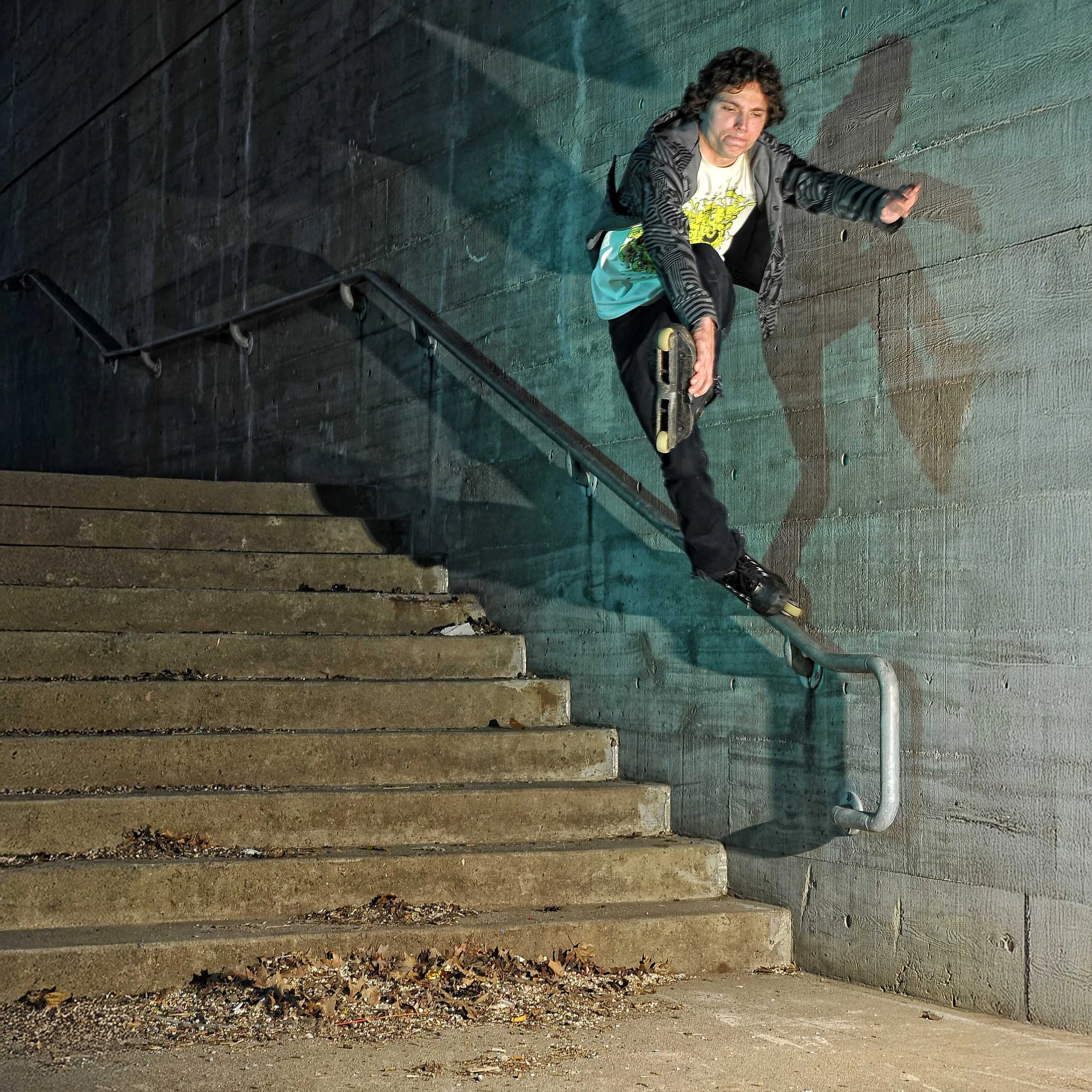 A person performing a skateboarding trick on a handrail at the top of concrete stairs outside, during nighttime.