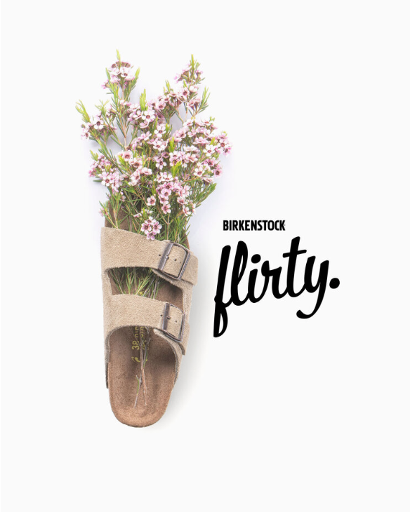 A sandal filled with pink flowering plants, placed next to the text 'Birkenstock flirty.'