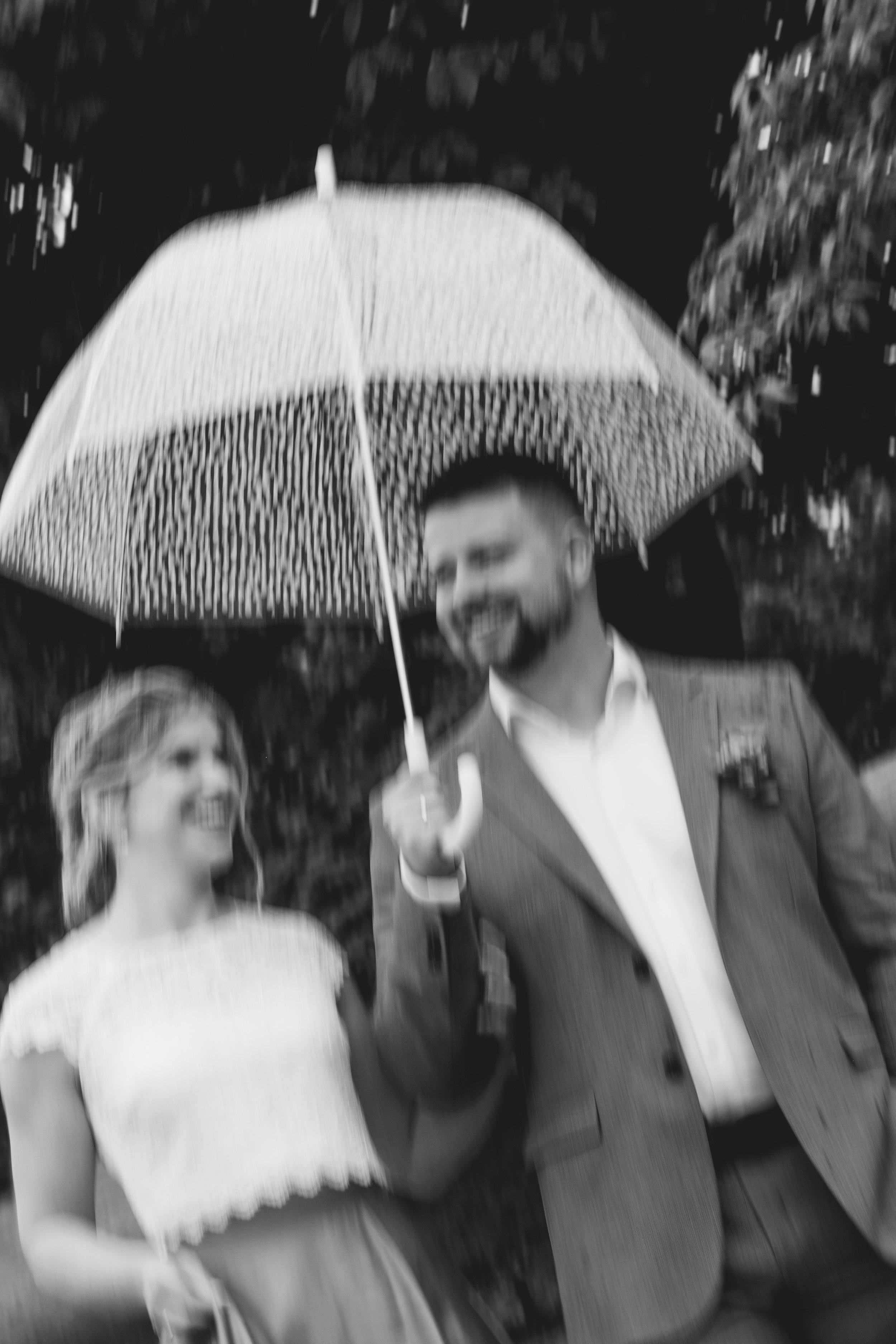 Zwei glückliche Menschen, ein Mann und eine Frau, die unter einem Regenschirm lachen, während es regnet.