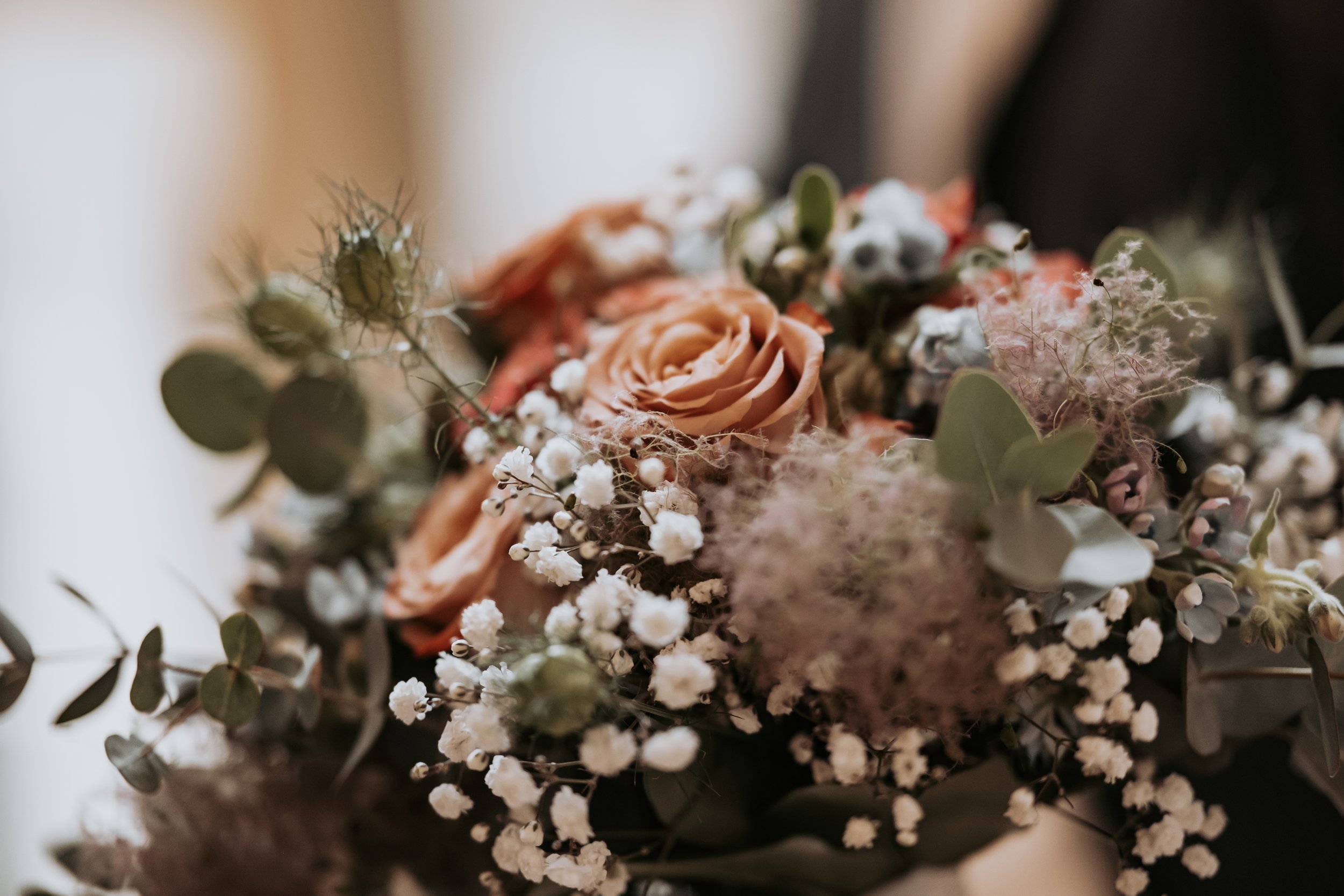 Blumenstrauß mit Rosen, kleinen weißen Blumen, Eukalyptus und anderen Blüten in Pastellfarben.