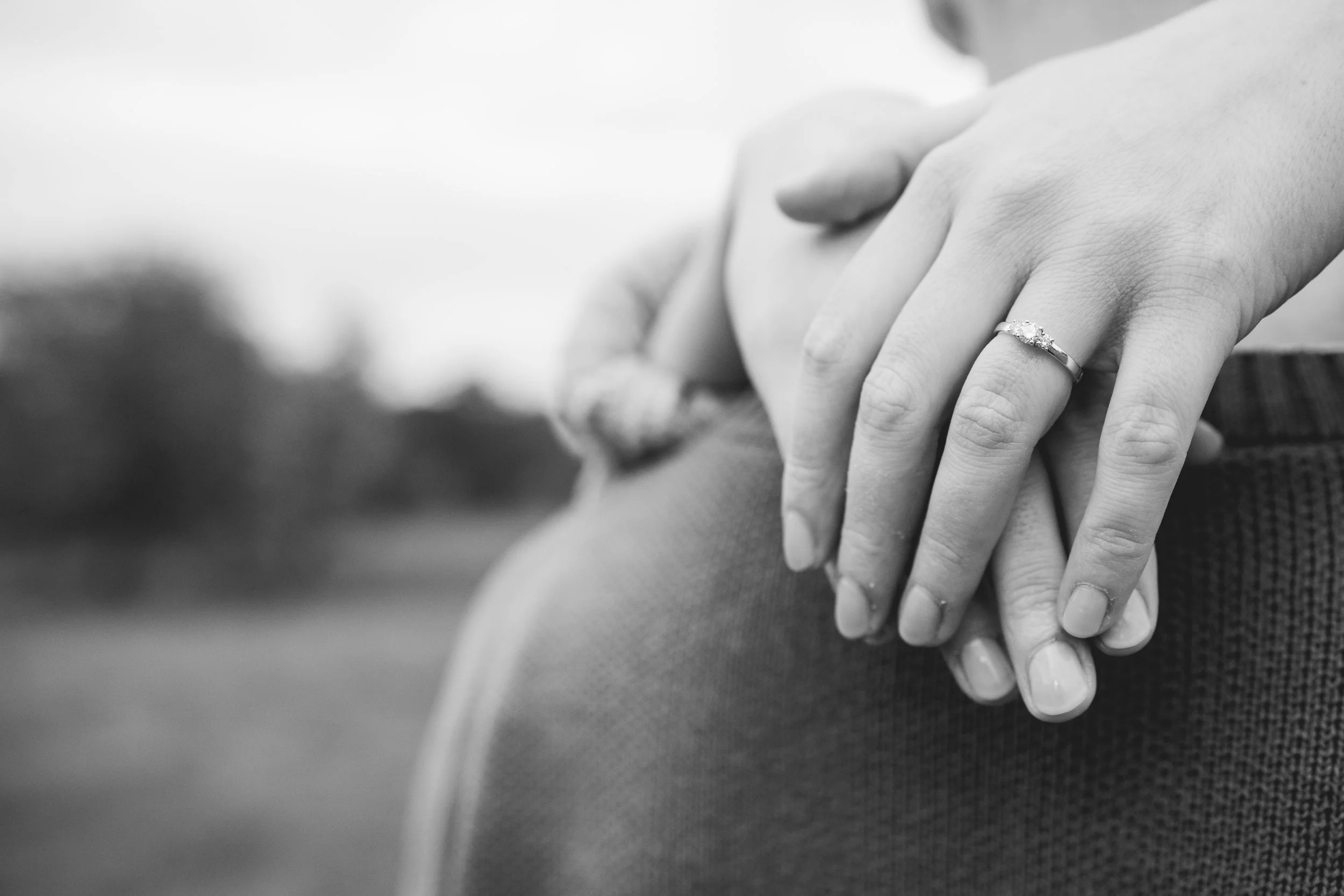 Schwarz-weiß-Foto von zwei Händen, die sich halten, mit einem Ehering am Ringfinger der linken Hand.