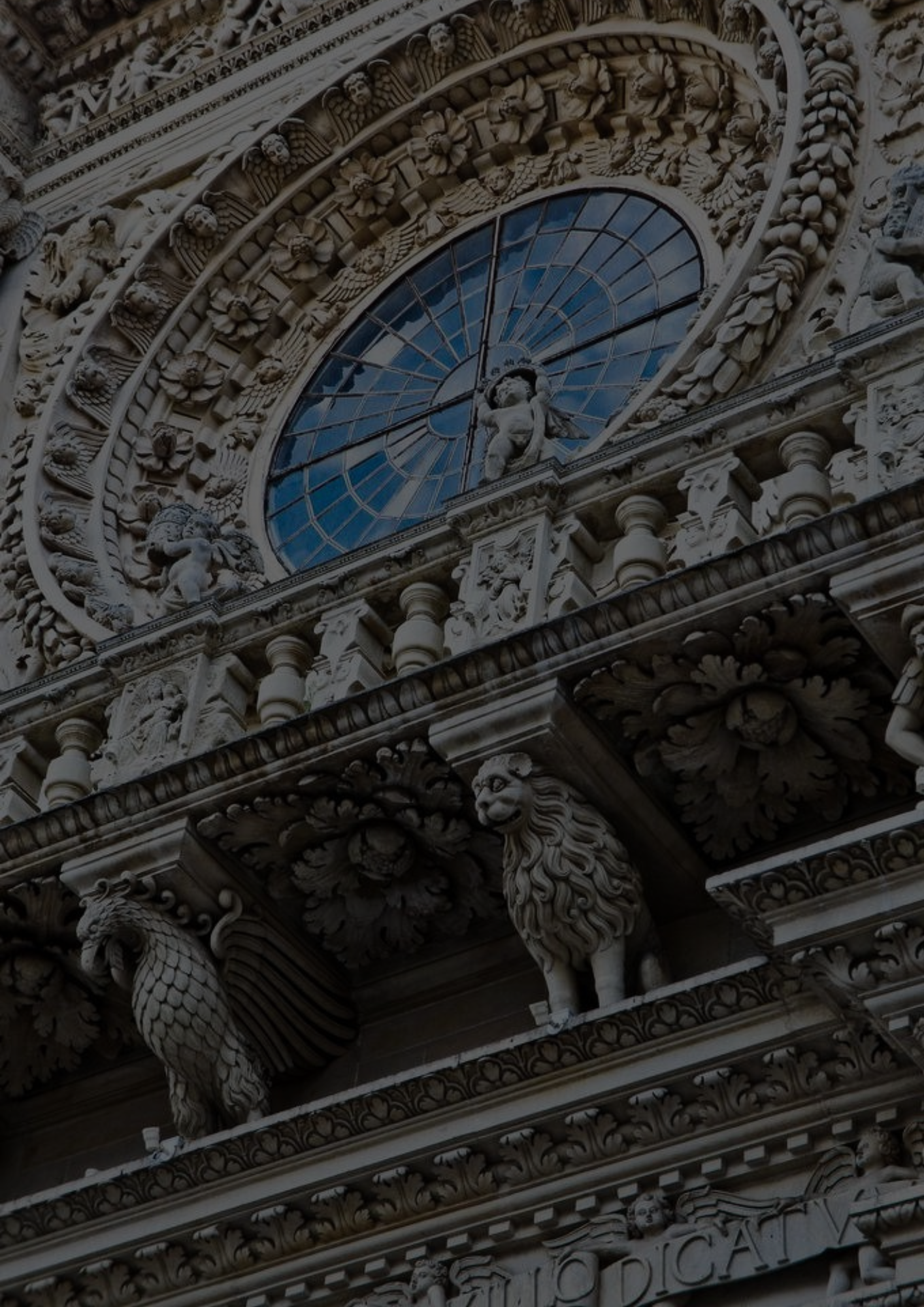 Detailreiches gotisches Bauwerk mit kunstvollen Verzierungen, Hasen- und Löwenfiguren, einem großen Uhrenfenster und geschwungenen Ornamenten aus Stein.