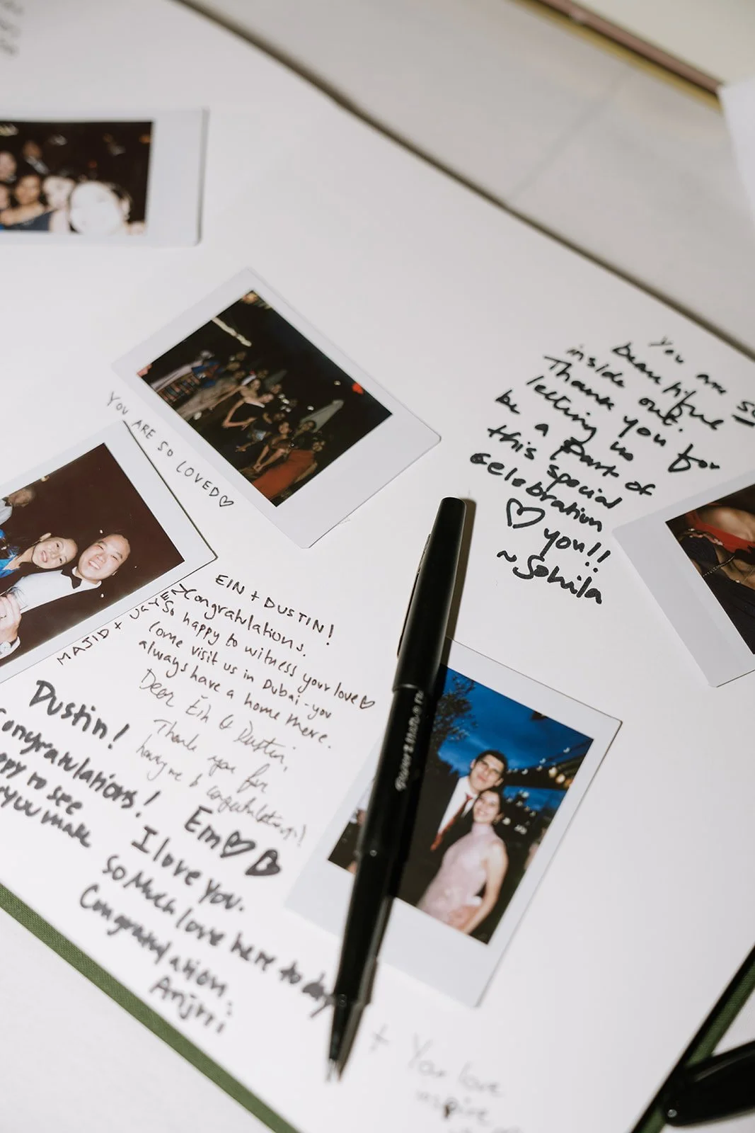 Guest book with handwritten notes, photographs, and a black pen lying on top