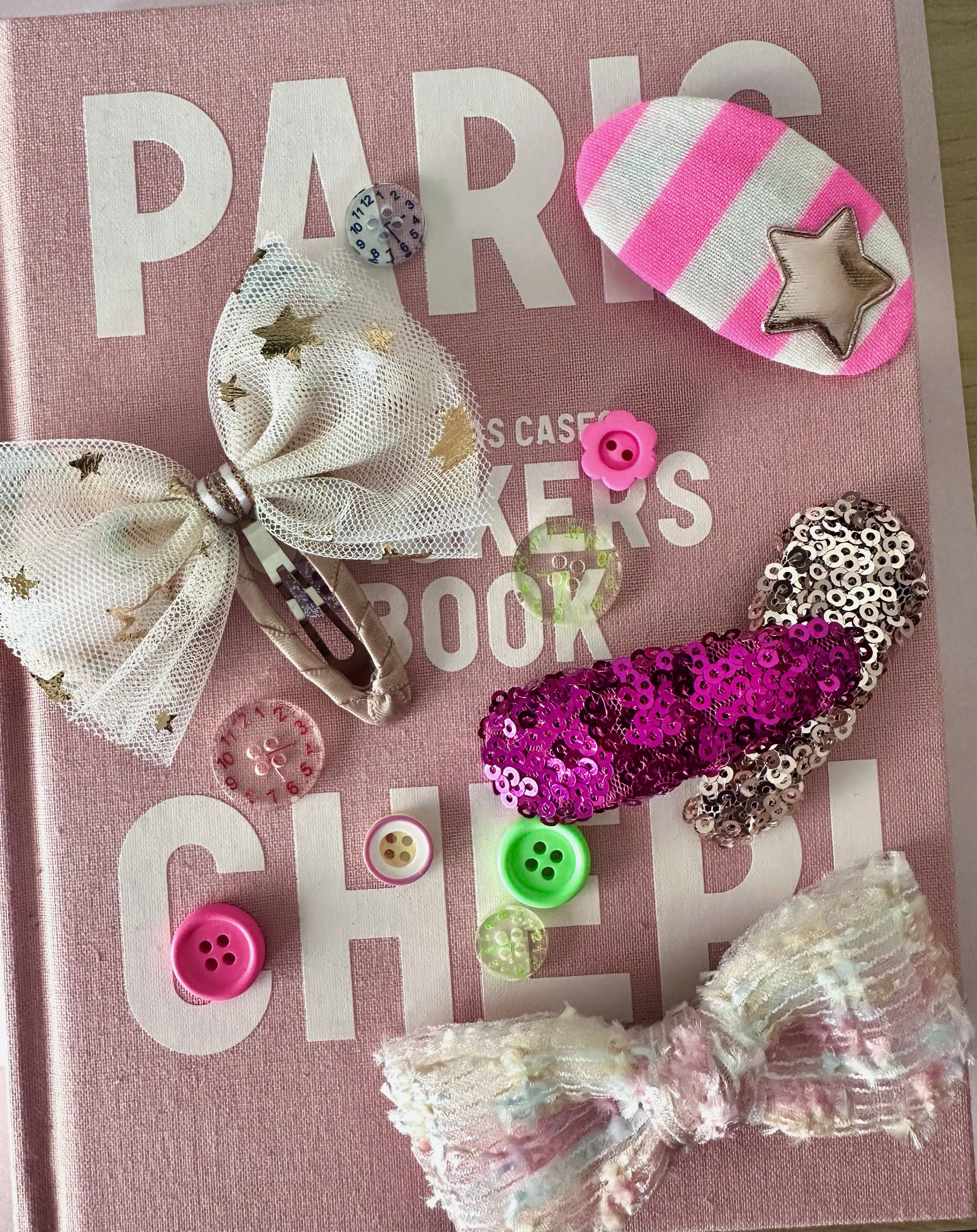 Pink scrapbook titled 'PARKER'S BOOK' decorated with various colorful craft items including sequined bows, buttons, a star patch, and small decorative pieces.