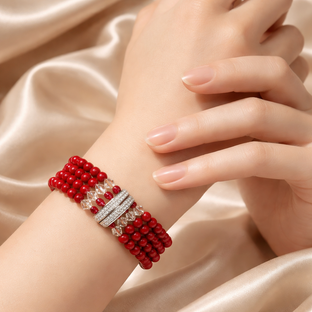 Close-up of a woman's wrist adorned with a red beaded bracelet with silver accents and a sparkling gemstone, resting on her hand.