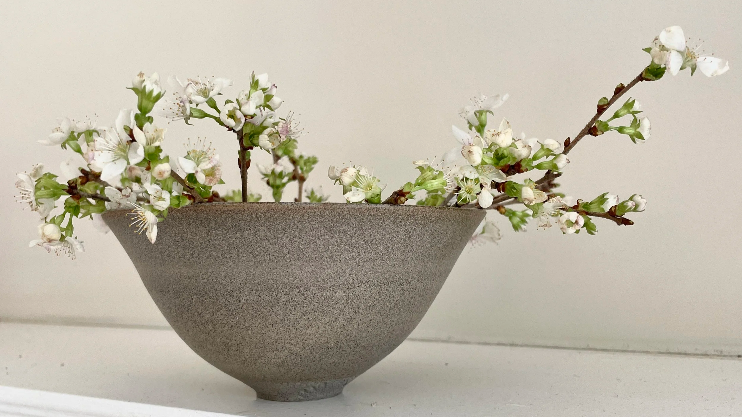 Handmade stoneware bowl by luxury contemporary ceramics studio FOUND with fresh apple blossom cuttings
