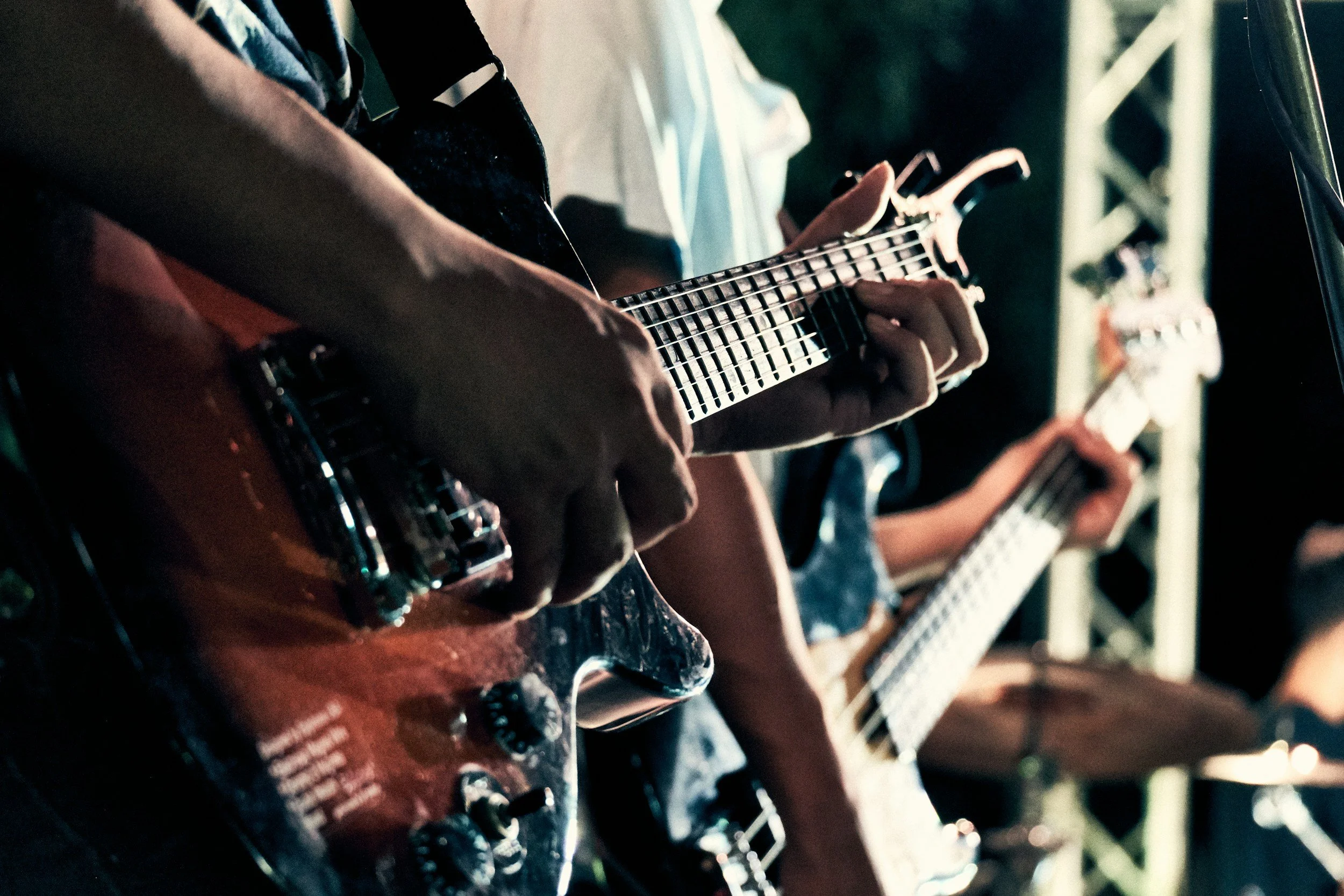 Close-up of people playing electric guitars during a band performance at night