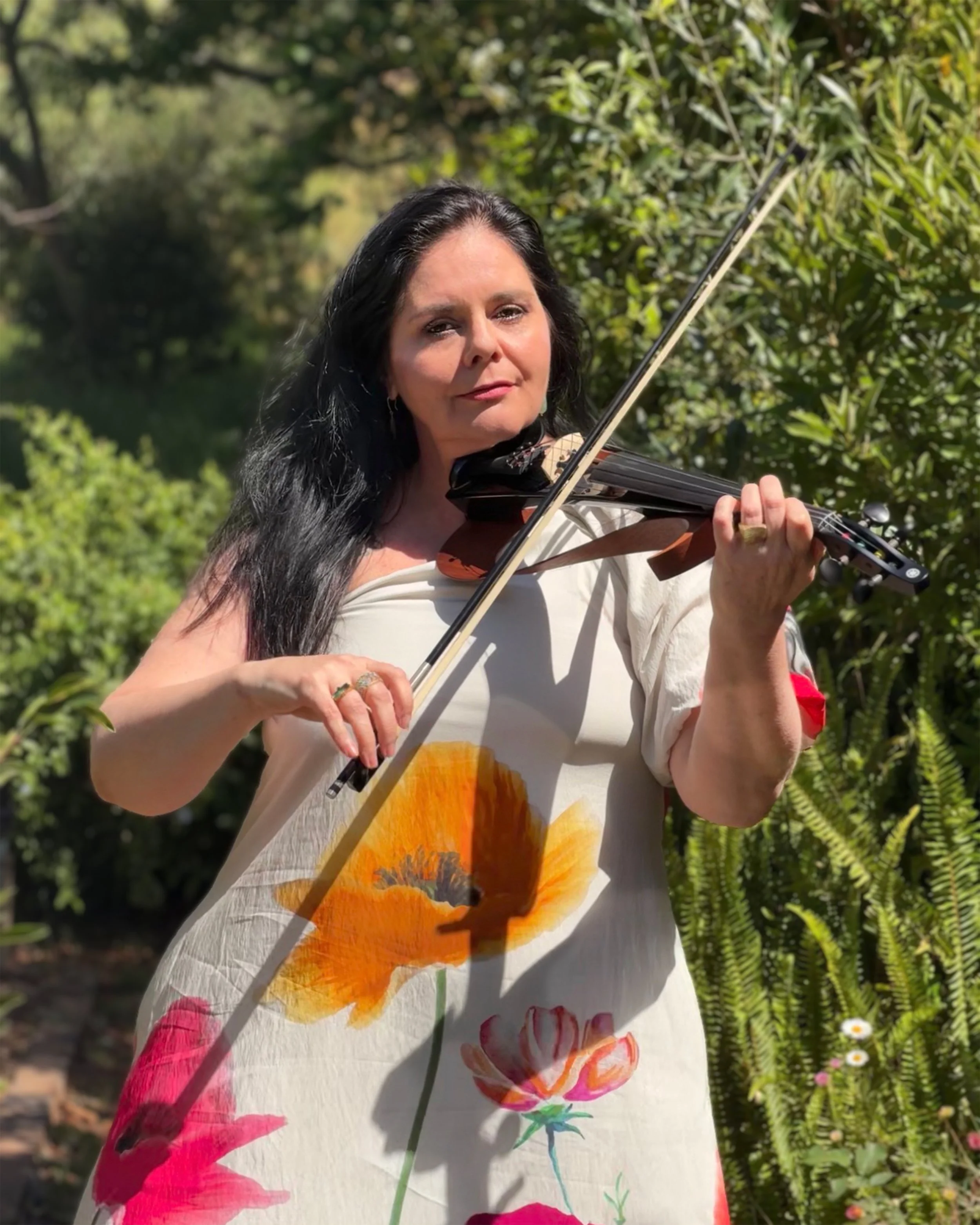 Cape Town violinist Larah Eksteen performing on acoustic violin in a lush outdoor garden setting.