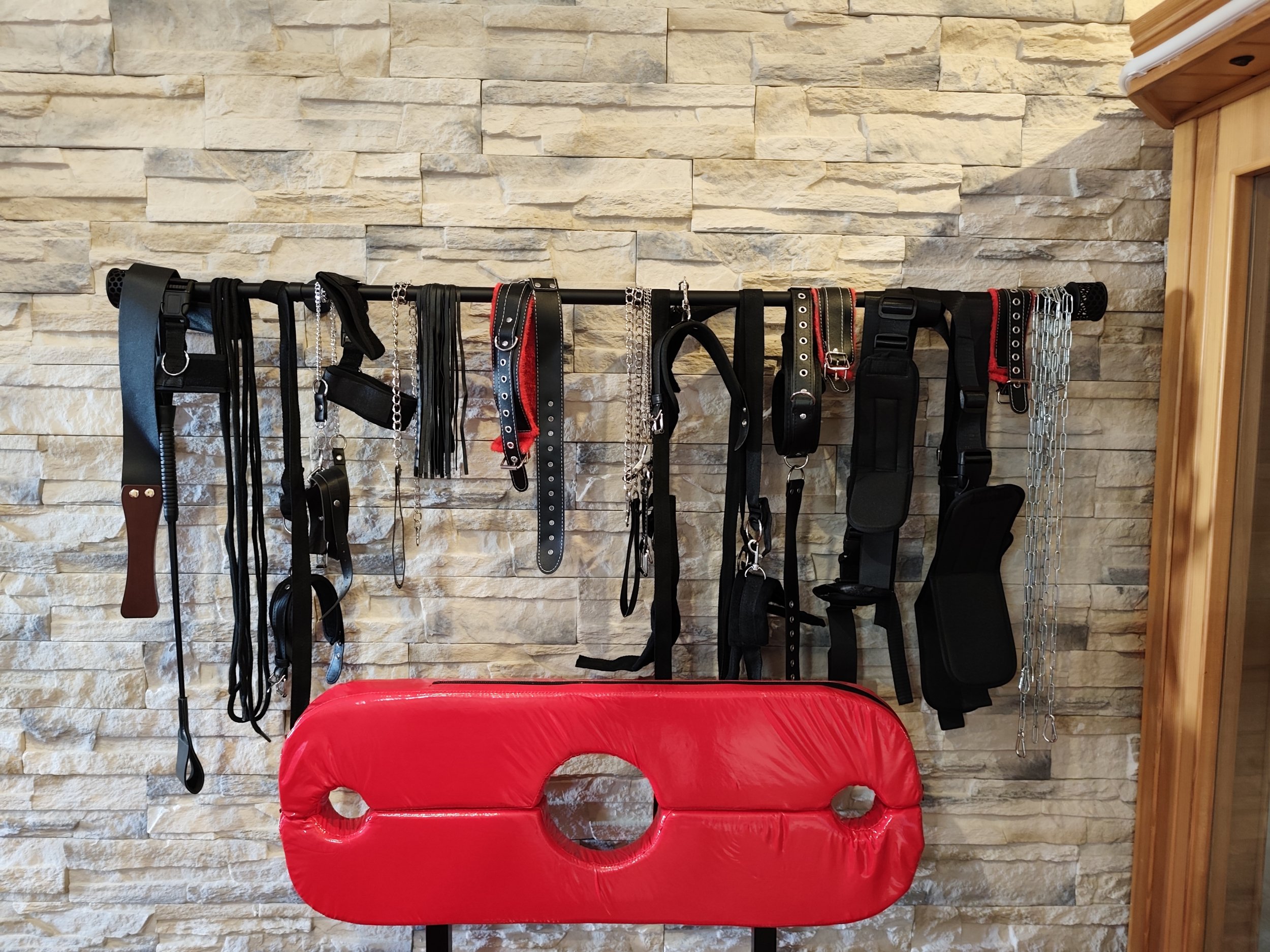 Espace donjon avec accessoires et mur en pierre dans la love room Villa Donuts.