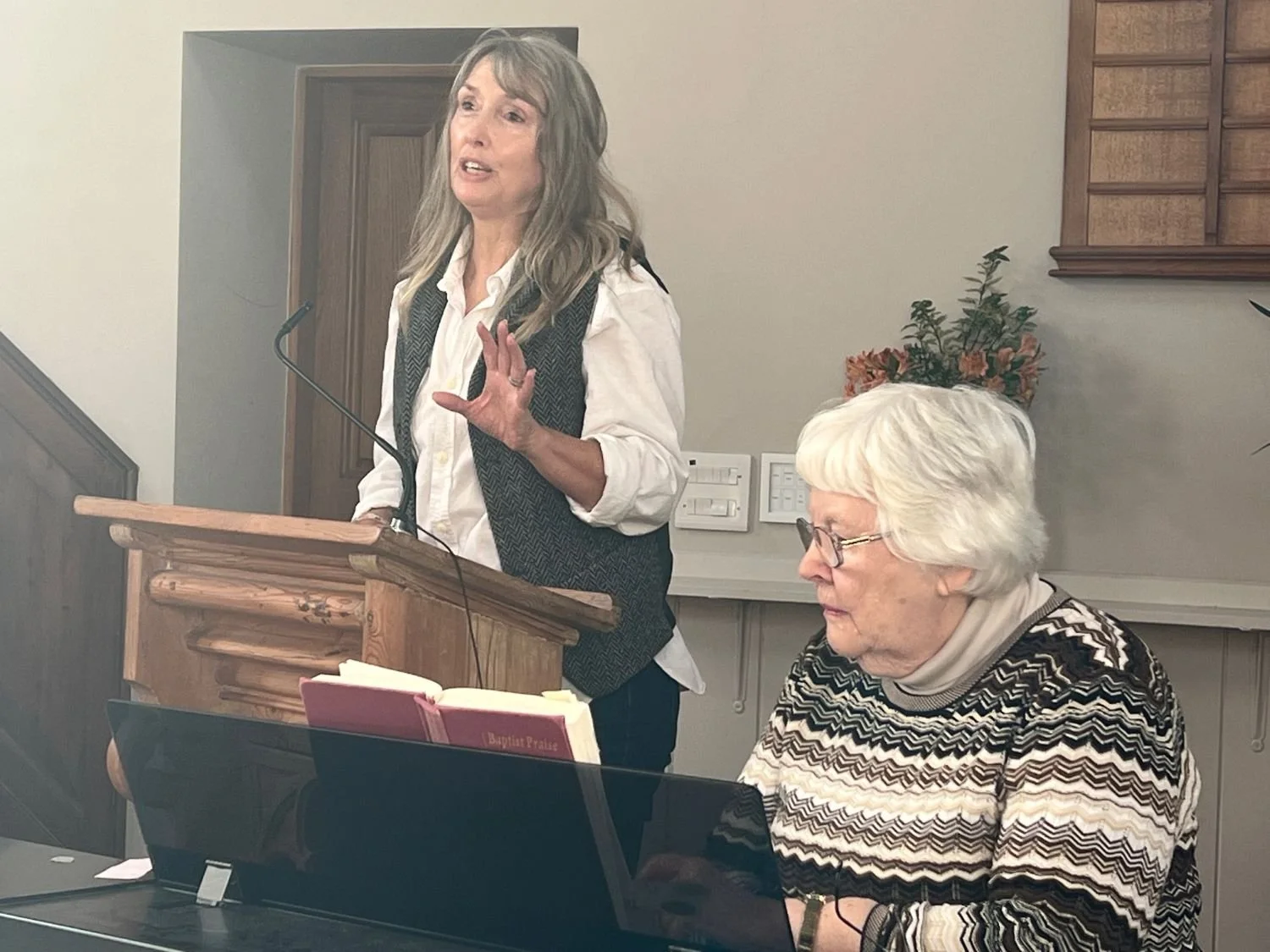 Person at lectern speaking, person at keyboard