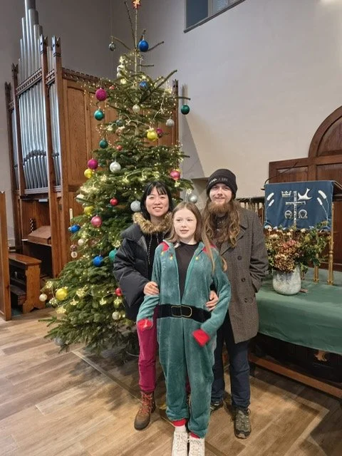 three people by a Christmas Tree