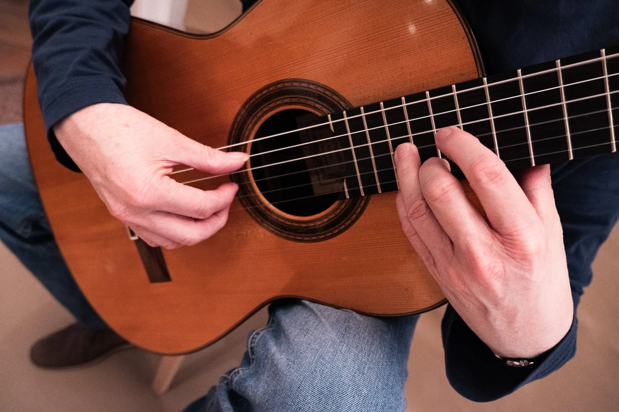 Eine ausschnittsweise Gitarre mit zwei Händen, die auf ihr spielen.