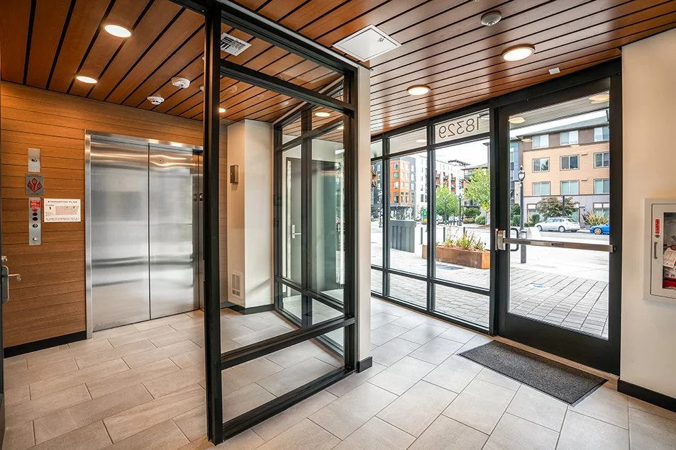 Main lobby showing the elevator, glass vestibule, and street-facing entry doors.