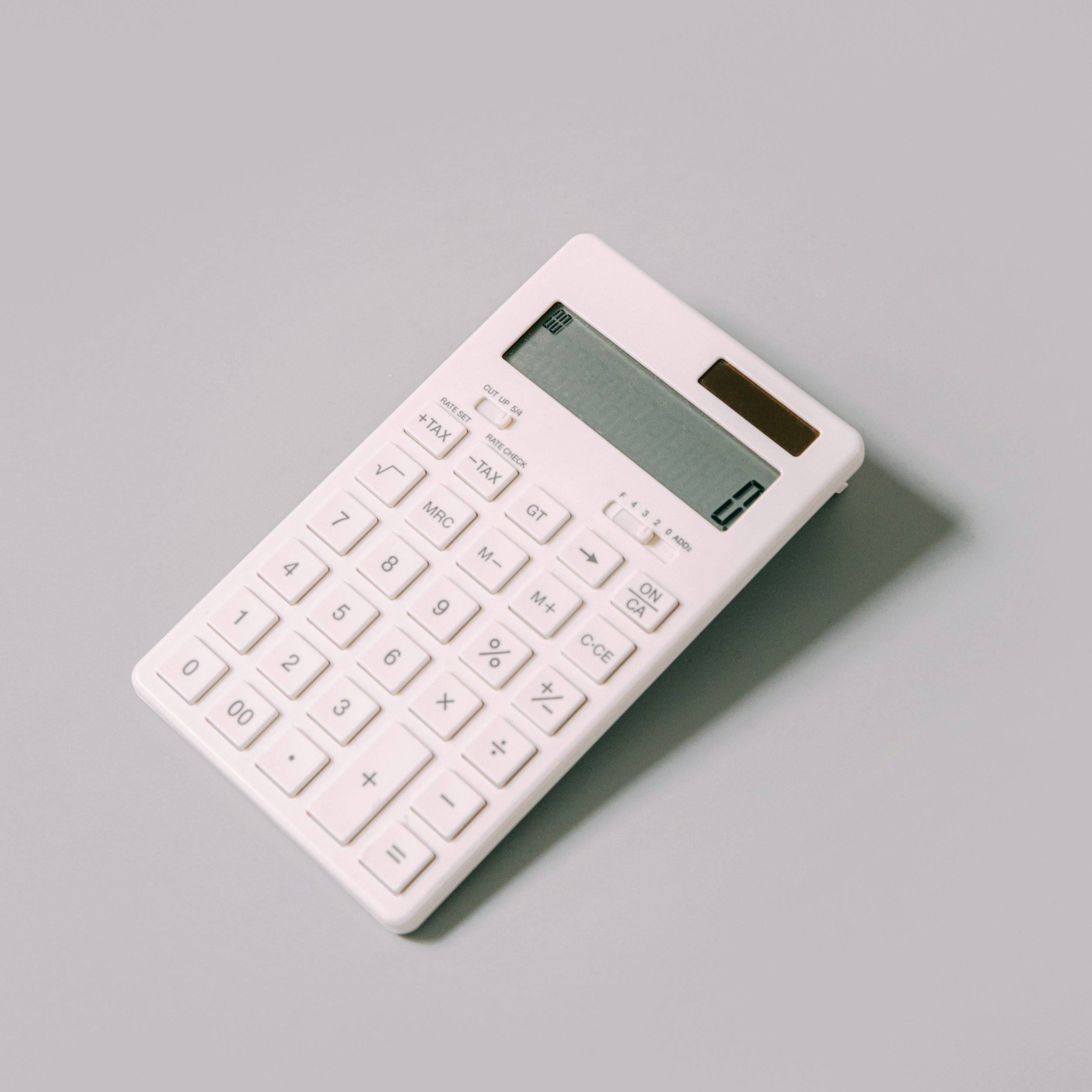 White calculator with a digital display on a gray surface.