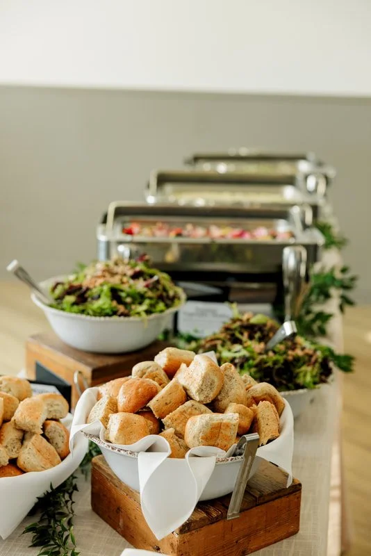 Buffet table with bowls of croutons, salads, and other dishes in metal chafing dishes.