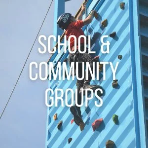 A person climbing an outdoor blue rock wall with the text 'School & Community Groups' overlaid.