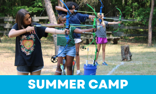 Four children outdoors at a summer camp practicing archery with bows and arrows.