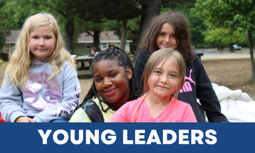Four young girls sitting outdoors, smiling at the camera, with trees and a park in the background, and a banner that says 'YOUNG LEADERS' at the bottom.