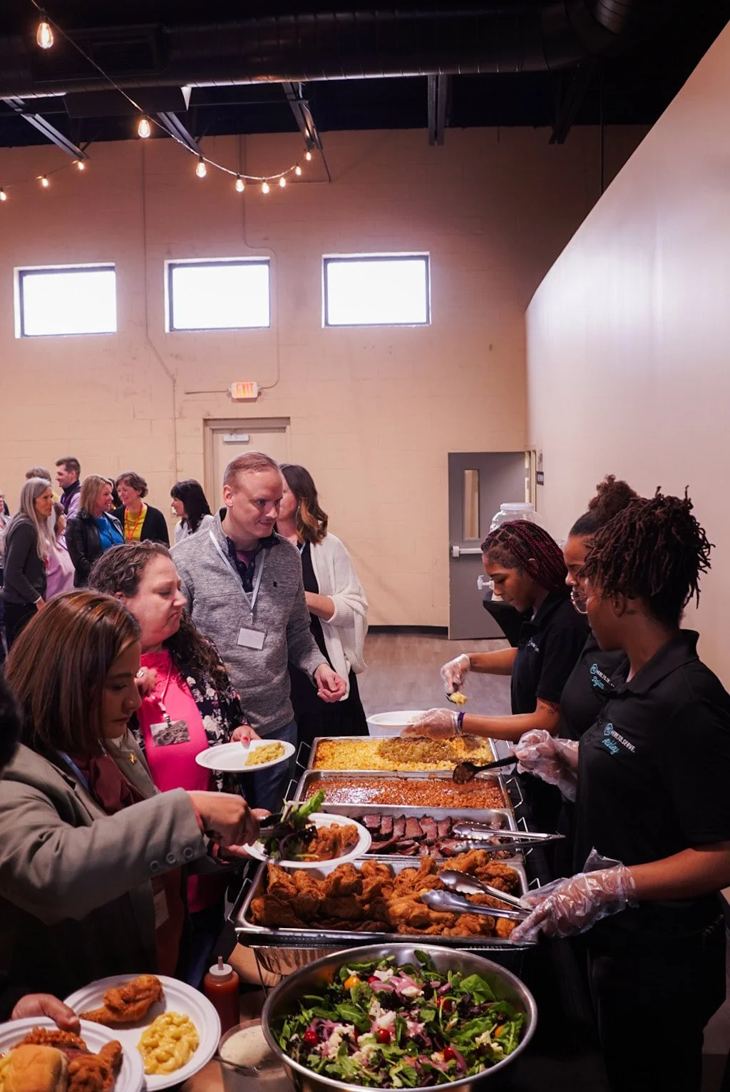 People serving themselves food at a buffet table during a gathering.