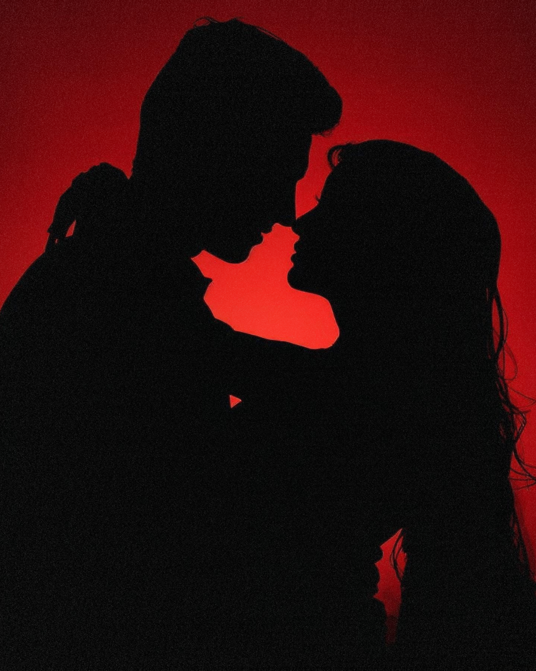 Silhouette of a couple facing each other with noses touching, set against a red background.