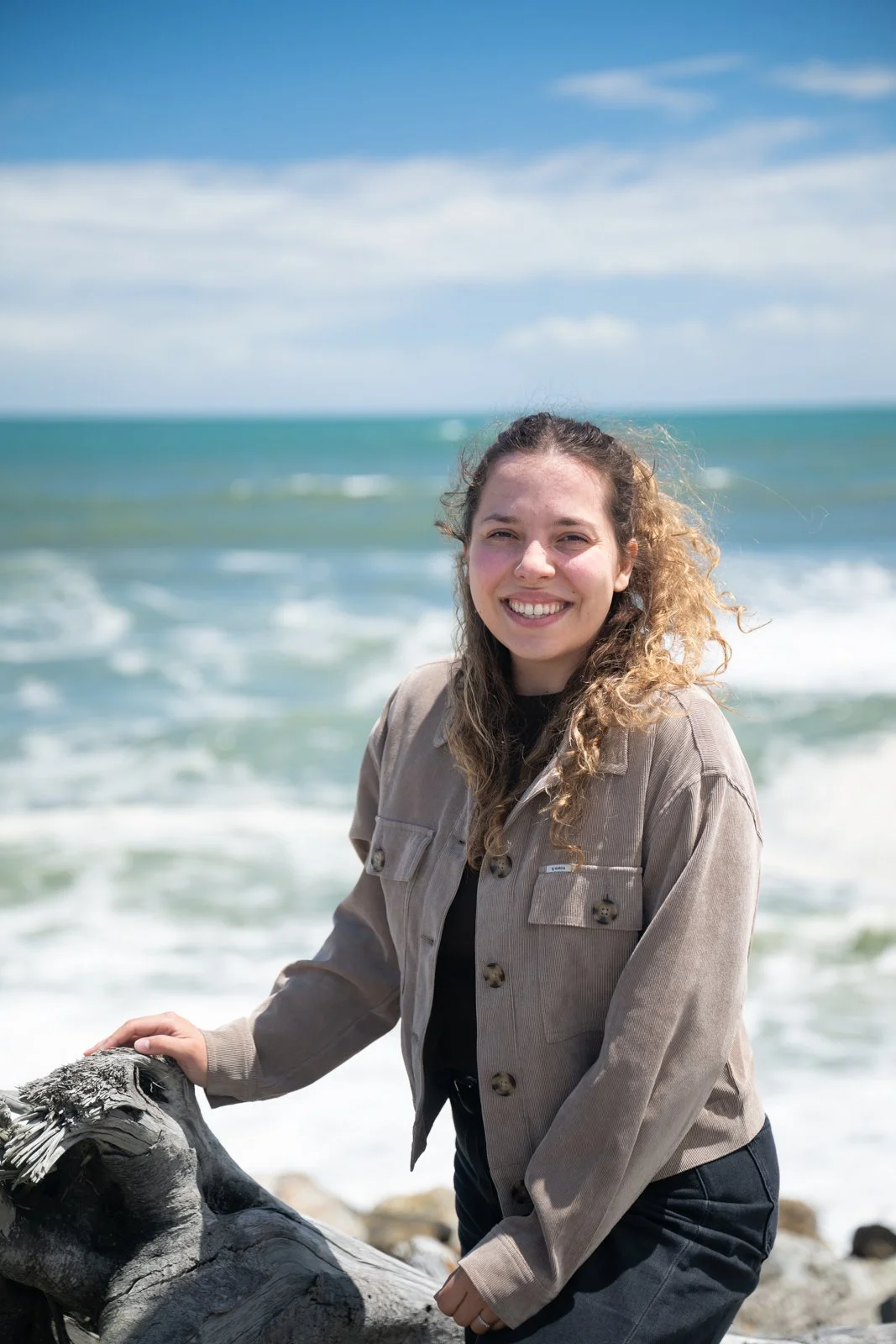 Junge Frau am Strand mit Meeresblick und Driftwood in der Hand