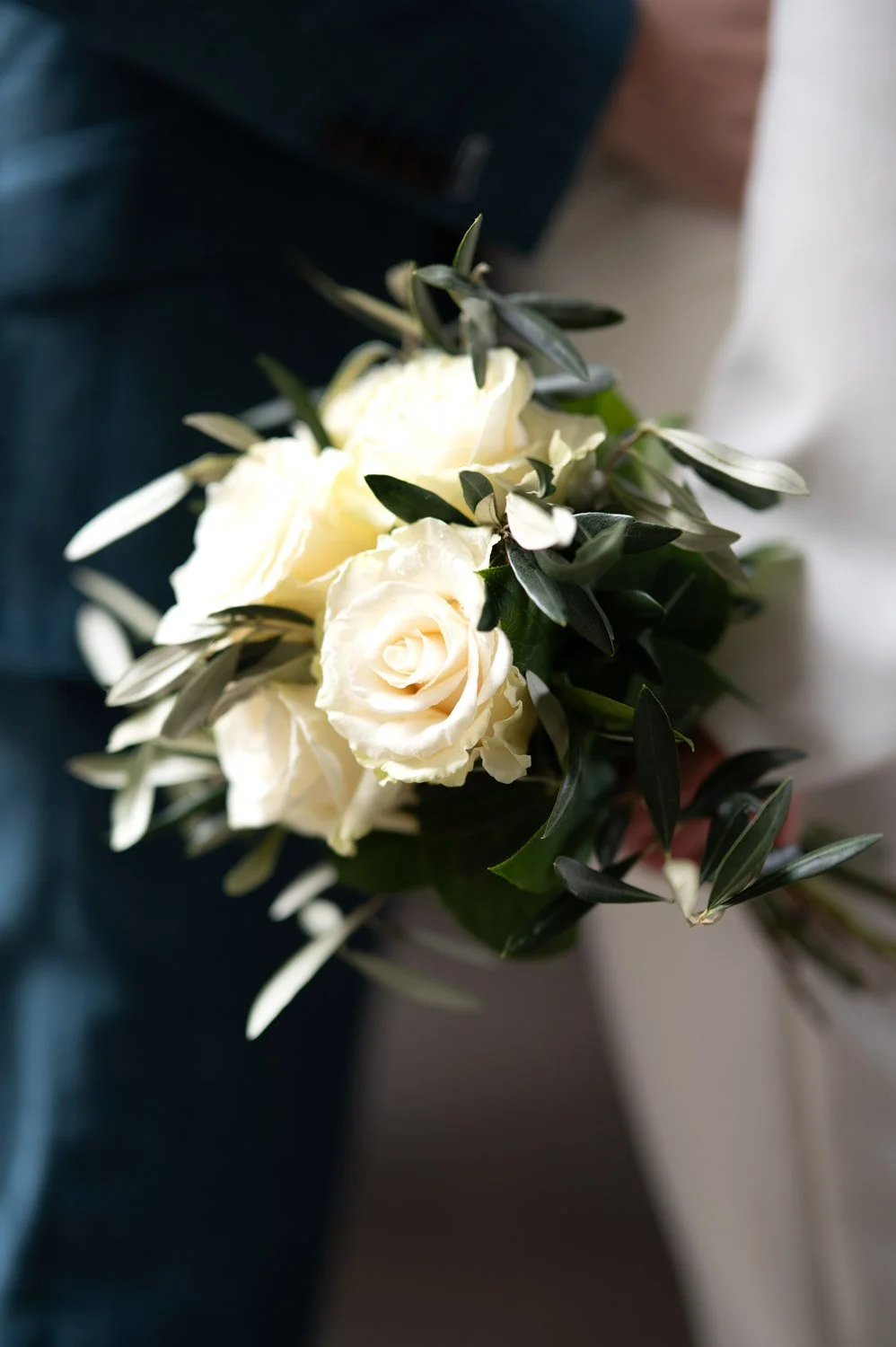 Weiße Rosen mit grünen Blättern in einem Blumenstrauß.