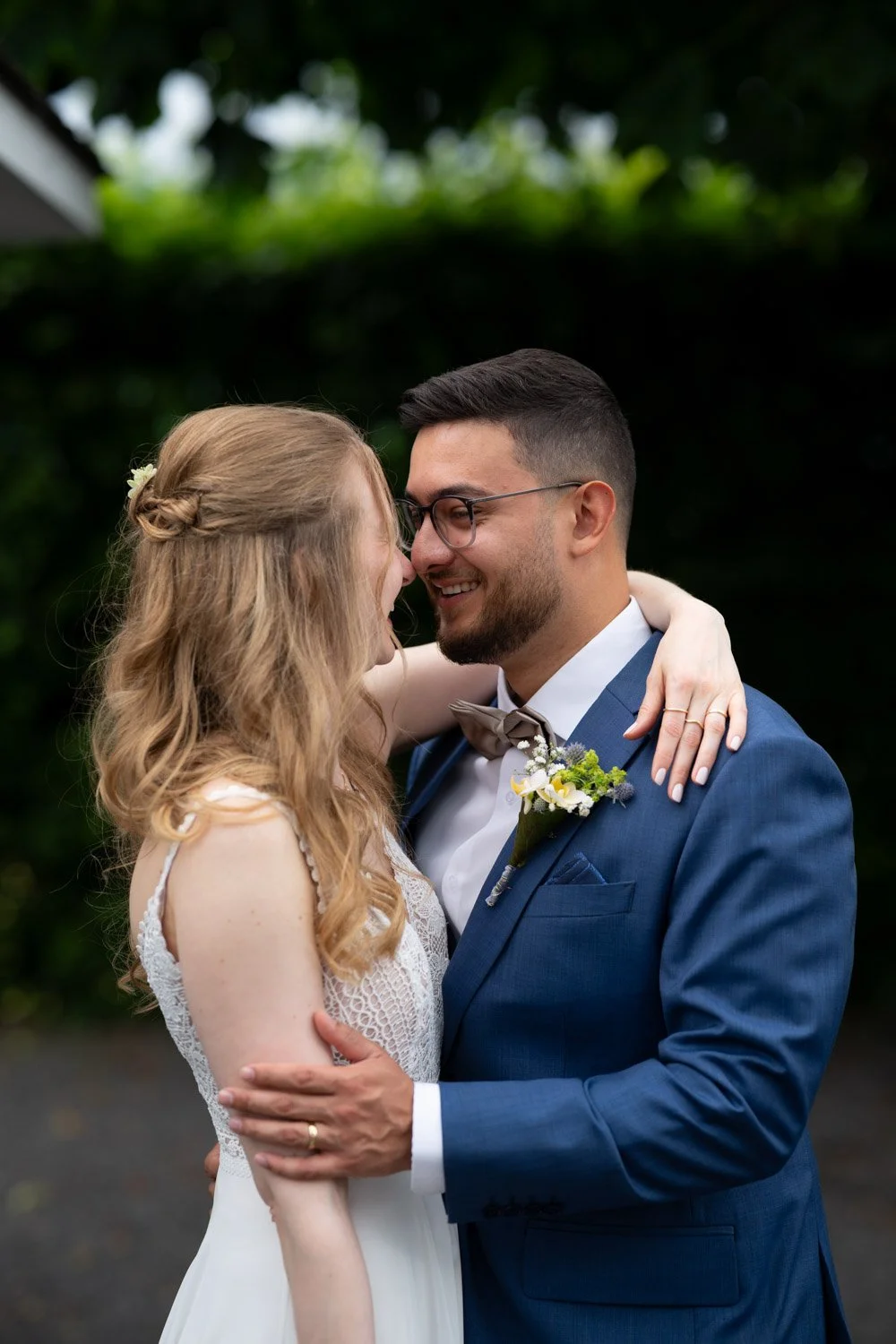 Ein verliebtes Brautpaar umarmt sich im Garten, lächelnd und liebevoll.