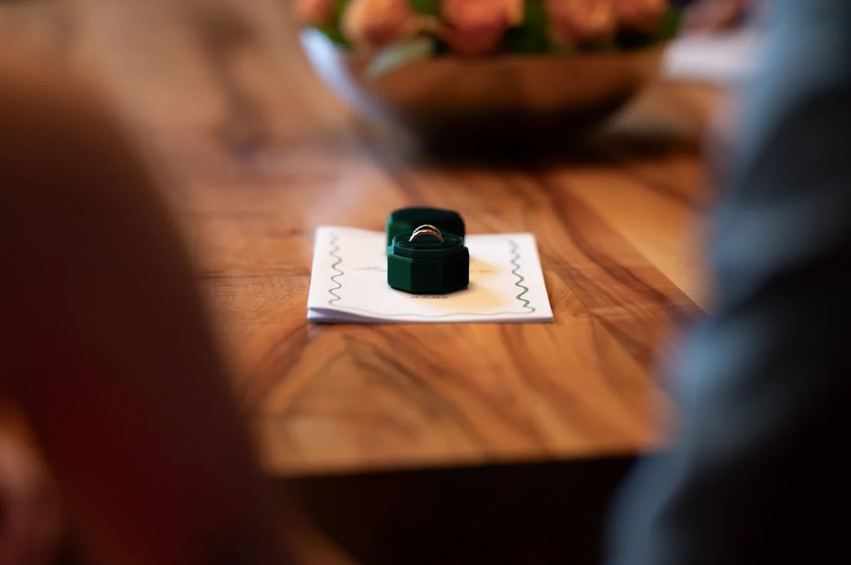 Ein Verlobungsring auf einem weißen Zettel mit schwarzen Zickzacklinien, auf einem Holztisch.