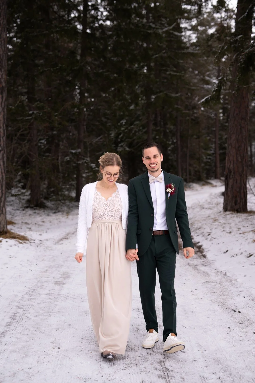 Ein verliebtes Paar in formeller Kleidung, das im Winter in einem verschneiten Wald spazieren geht.